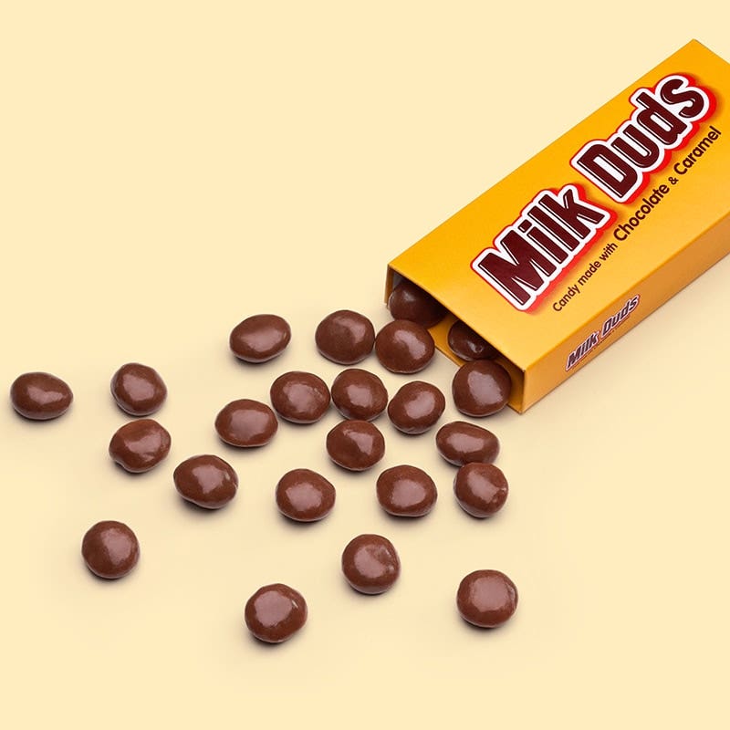 Milk Duds poured over tan background