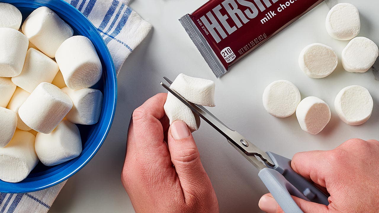 person cutting marshmallows in half with scissors